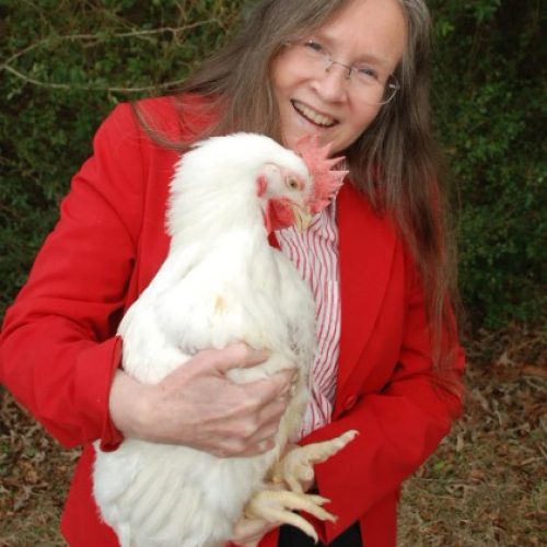 Nancy Hinkle dressed in bright red holding a chicken